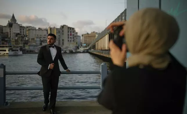 Mucahit Uzun wearing his wedding suit poses during a photo session at Galata bridge, in Istanbul, Turkey, Wednesday, July 30, 2025. (AP Photo/Emrah Gurel)