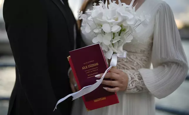 Damla Avci, right, and her husband Mustafa Ertan pose during a photo session at Galata bridge in Istanbul, Turkey, Thursday, July 31, 2025. (AP Photo/Emrah Gurel)