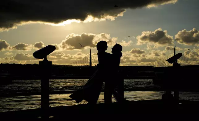 Sude Keles, left, and her husband Suat Keles pose during a photo session at Galata bridge in Istanbul, Turkey, Thursday, July 31, 2025. (AP Photo/Emrah Gurel)