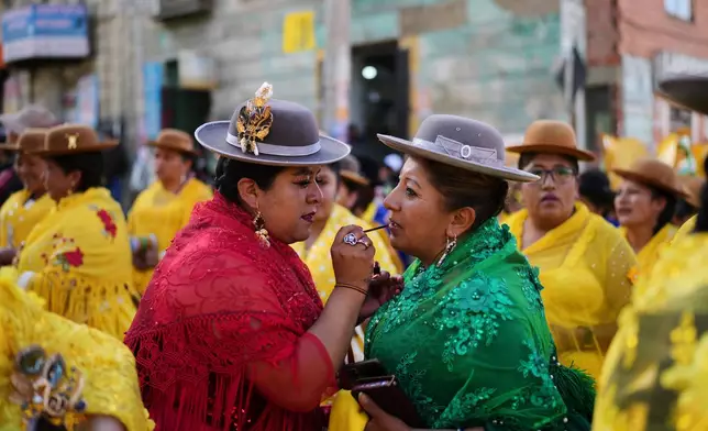 A supporter of presidential candidate Samuel Doria Medina applies lipstick on another at a campaign rally five days ahead of presidential elections, in La Paz, Bolivia, Tuesday, Aug. 12, 2025. (AP Photo/Natacha Pisarenko)