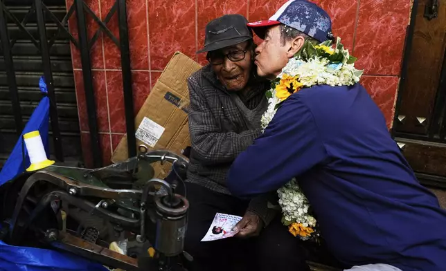Bolivian presidential candidate Jorge "Tuto" Quiroga plants a kiss on a shoemaker while campaigning ahead of the upcoming presidential election, in La Paz, Bolivia, Thursday, Aug. 7, 2025. (AP Photo/Juan Karita)