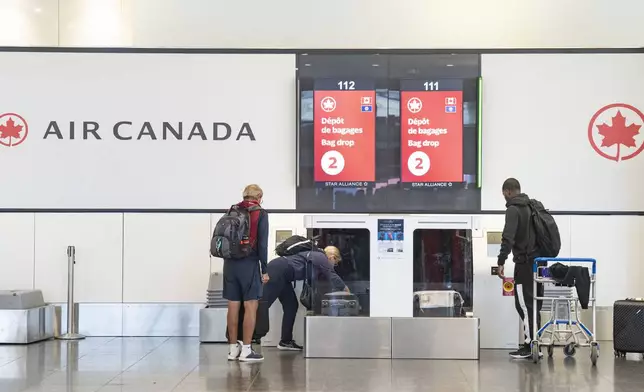 Air Canada travellers load their luggage at Montreal-Pierre Elliott Trudeau International Airport in Dorval, Que., on Tuesday, Aug. 19, 2025. (Christinne Muschi/The Canadian Press via AP)