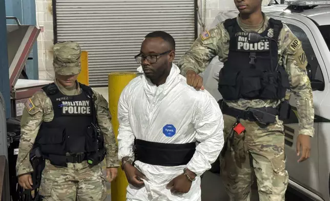 Sgt. Quornelius Radford, a suspect in the shooting of five soldiers at Fort Stewart, is escorted by military police into a booking room at the Liberty County Jail in Hinesville, Ga., Wednesday, Aug. 6, 2025. (AP Photo/Lewis M. Levine)