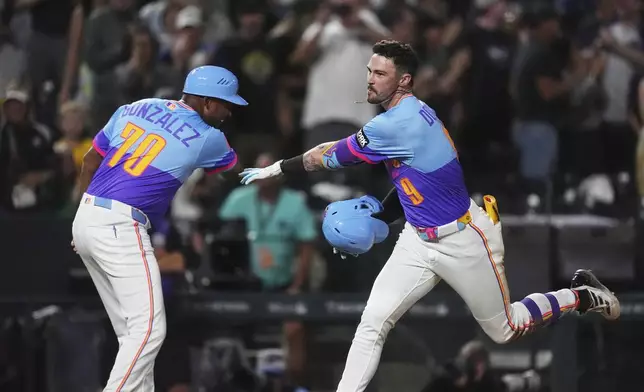 Colorado Rockies third base coach Andy González, left, congratulates Brenton Doyle as he circles the bases after hitting a two-run, walkoff home run off Pittsburgh Pirates relief pitcher Dennis Santana in the ninth inning of a baseball game Friday, Aug. 1, 2025, in Denver. (AP Photo/David Zalubowski)