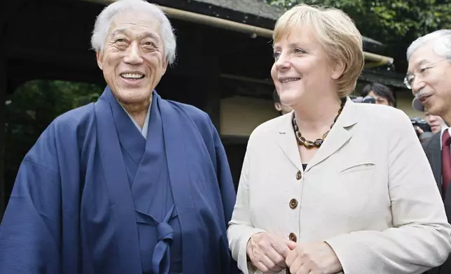 FILE - German Chancellor Angela Merkel, right, shares a light moment with Genshitsu Sen, left, the head of the Urasenke school, which teaches the history behind the Japanese tea ceremony, Aug. 31, 2007, in Kyoto, Japan. (AP Photo/Toru Yamanaka, Pool, File)