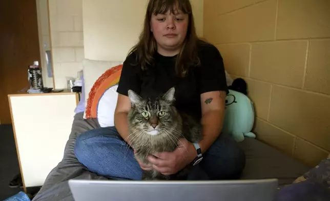 Student Molly Cheer sits with her pet comfort cat, Louie, in her dorm room at the University of Northern Colorado in Greeley, Colo., on Monday, Aug. 25, 2025. (AP Photo/Thomas Peipert)