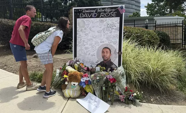 People leave flowers Monday, Aug. 11, 2025, at a makeshift memorial in honor of David Rose, the officer who was killed in the shooting at the U.S. Centers for Disease Control and Prevention headquarters in Atlanta. (AP Photo/Charlotte Kramon)