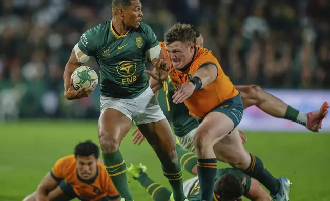 South Africa's Damian Willemse, left, is tackled by Australia's Max Jorgensen during a rugby championship test match between South Africa and Australia, at Ellis Park stadium in Johannesburg, South Africa, Saturday, Aug. 16, 2025. (AP Photo/Frans Lombard)