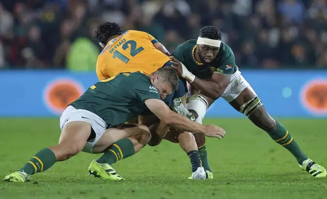 South Africa's captain Siya Kolisi, right, with his teammate tackles Australia's Len Ikitau, centre, during a rugby championship test match between South Africa and Australia, at Ellis Park stadium in Johannesburg, South Africa, Saturday, Aug. 16, 2025. (AP Photo/Frans Lombard)