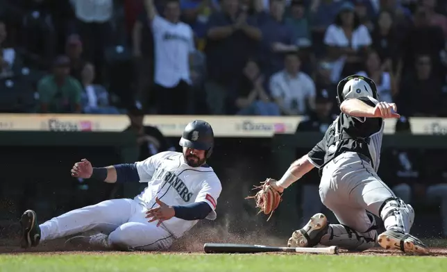Seattle Mariners' Eugenio Suárez, left, beats a tag by Chicago White Sox catcher Kyle Teel, right, to score the winning run off a hit by Dominic Canzone during the 11th inning of a baseball game, Thursday, Aug. 7, 2025, in Seattle. (AP Photo/Jason Redmond)