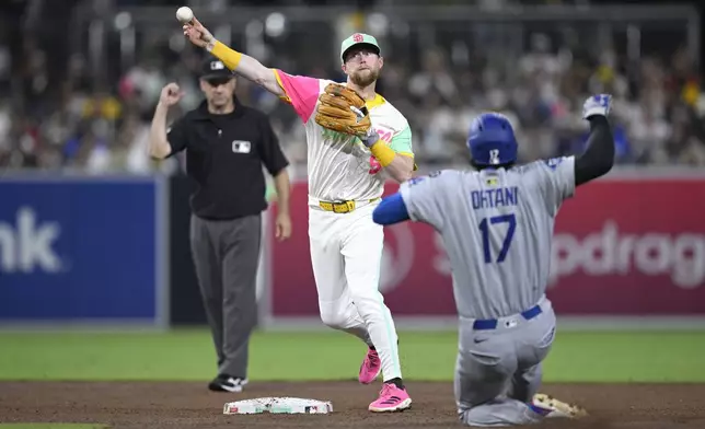 San Diego Padres second baseman Jake Cronenworth, center, throws to first base after forcing out Los Angeles Dodgers' Shohei Ohtani (17) at second base to complete a double play during the sixth inning of a baseball game Friday, Aug. 22, 2025, in San Diego. (AP Photo/Orlando Ramirez)