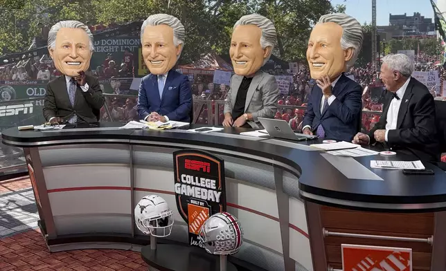 ESPN's Lee Corso, right, reacts as his colleagues don Corso heads during ESPN's "College GameDay," before the NCAA college football game between Ohio State and Texas, Saturday, Aug. 30, 2025, in Columbus, Ohio. (AP Photo/Jospeh Reedy)
