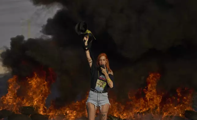 An activist blocks a highway during a protest demanding the immediate release of hostages held by Hamas and calling for the Israeli government to reverse its decision to take over Gaza City and other areas in the Gaza Strip, near the city of Lod, Israel, Tuesday, Aug. 26, 2025. (AP Photo/Ohad Zwigenberg)