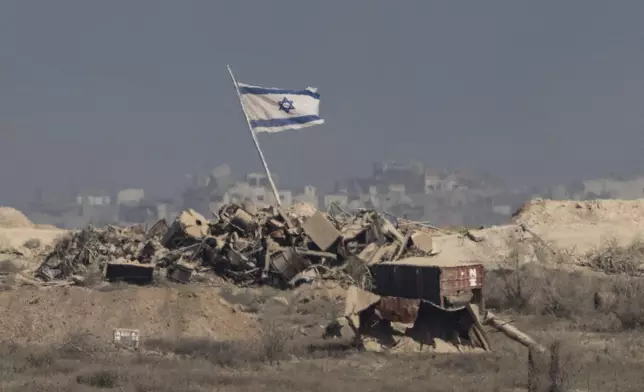 An Israeli flag waves over debris in an area of the Gaza Strip, as seen from southern Israel, Tuesday, Aug. 26, 2025. (AP Photo/Maya Levin)