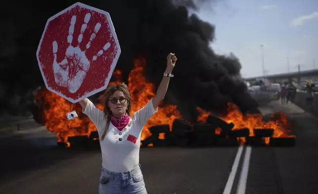 A demonstrator blocks a highway during a protest demanding the immediate release of all hostages held by Hamas and calling for the end of the war in the Gaza Strip, near Modiin, Israel, Tuesday, Aug. 26, 2025. (AP Photo/Ohad Zwigenberg)
