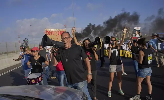 Activists block a highway during a protest demanding the immediate release of hostages held by Hamas and calling for the Israeli government to reverse its decision to take over Gaza City and other areas in the Gaza Strip, near the city of Lod, Israel, Tuesday, Aug. 26, 2025. (AP Photo/Ohad Zwigenberg)