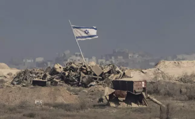 An Israeli flag waves over debris in an area of the Gaza Strip, as seen from southern Israel, Tuesday, Aug. 26, 2025. (AP Photo/Maya Levin)