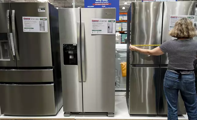 A woman measures a new appliance at a store in Kennesaw, Ga., on Thursday, Aug. 14, 2025. (AP Photo/Mike Stewart)