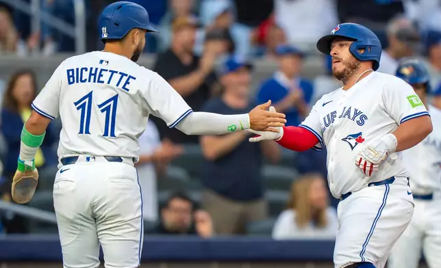 Toronto Blue Jays' Alejandro Kirk, center, is congratulated by Bo Bichette (11) after they scored on his two-run home run in first-inning baseball game action against the Minnesota Twins in Toronto, Monday, Aug. 25, 2025. (Frank Gunn/The Canadian Press via AP)