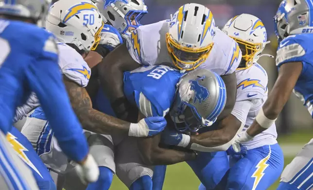 Detroit Lions quarterback Hendon Hooker (2) is sacked by Los Angeles Chargers linebacker Caleb Murphy (50), TeRah Edwards (94) and safety Emany Johnson, right, in the second half of the Pro Football Hall of Fame NFL preseason game Thursday, July 31, 2025, in Canton, Ohio. (AP Photo/David Richard)
