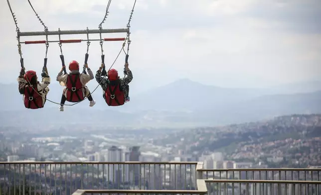 Tourists enjoy a giant swing overlooking the city on Trebevic mountain near Sarajevo, Bosnia, Tuesday, Aug. 5, 2025. (AP Photo/Armin Durgut)
