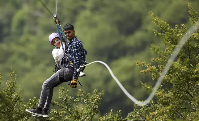 Tourists ride on a zip line on Bjelasnica mountain near Sarajevo, Bosnia, Tuesday, Aug. 5, 2025. (AP Photo/Armin Durgut)
