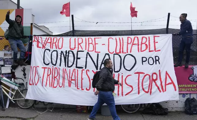 Opponents of former President Alvaro Uribe hang protest signs outside the court on the day he was sentenced to 12 years under house arrest for witness tampering and bribery in Bogota, Colombia, Friday, Aug. 1, 2025. (AP Photo/Fernando Vergara)