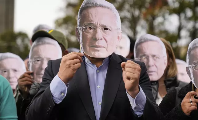 Supporters of former Colombian President Alvaro Uribe hold cutouts of his face outside the court where a verdict is expected in his trial for witness tampering in Bogota, Colombia, Monday, July 28, 2025. (AP Photo/Fernando Vergara)