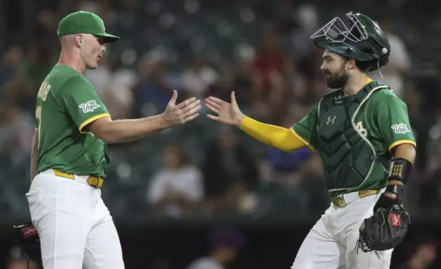 Athletics pitcher Sean Newcomb, left, and catcher Shea Langeliers, right, celebrate the teams win over the Arizona Diamondbacks in a baseball game Friday, Aug. 1, 2025, in West Sacramento, Calif. (AP Photo/Scott Marshall)
