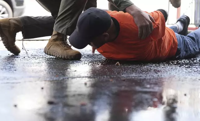 A man is detained by immigration agents at a car wash on Friday, Aug. 15, 2025, in Montebello, Calif. (AP Photo/Gregory Bull)