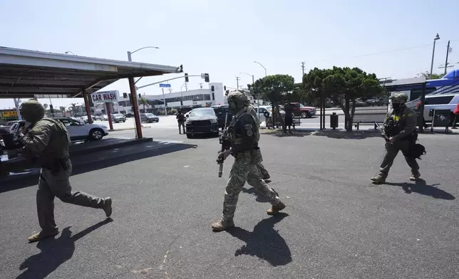 Immigration agents conduct an operation at a car wash on Friday, Aug. 15, 2025, in Montebello, Calif. (AP Photo/Gregory Bull)