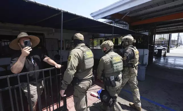 Immigration agents conduct an operation at a car wash on Friday, Aug. 15, 2025, in Montebello, Calif. (AP Photo/Gregory Bull)