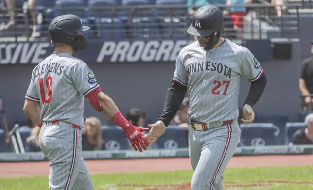 Minnesota Twins' Ryan Jeffers (27) scores on a double by Royce Lewis and is congratulated by Kody Clemens (18) during the first inning of a baseball game, Sunday, Aug. 3, 2025, in Cleveland. (AP Photo/Phil Long)