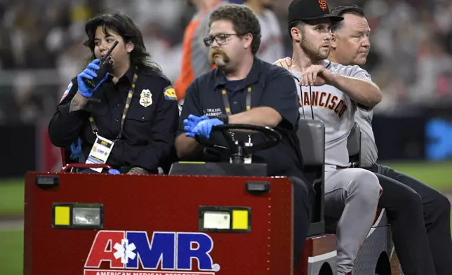 San Francisco Giants starting pitcher Landen Roupp, second from right, is taken out in a cart after being hit by a line drive during the third inning of a baseball game against the San Diego Padres Wednesday, Aug. 20, 2025, in San Diego. (AP Photo/Orlando Ramirez)