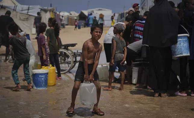Displaced Palestinians gather to collect water from a truck during a heat wave at a makeshift tent camp in Khan Younis, Gaza Strip, Wednesday, Aug. 13, 2025. (AP Photo/Abdel Kareem Hana)
