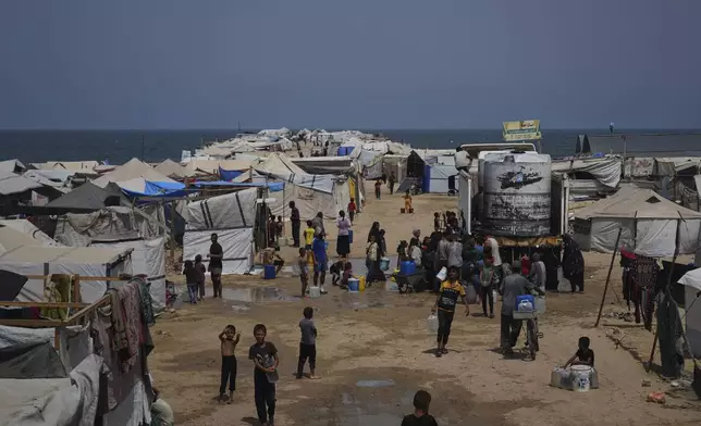 Displaced Palestinians gather to collect water from a truck during a heat wave at a makeshift tent camp in Khan Younis, Gaza Strip, Wednesday, Aug. 13, 2025. (AP Photo/Abdel Kareem Hana)