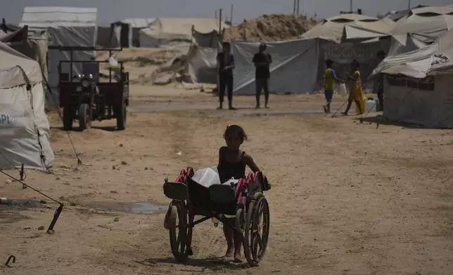 A Palestinian girl pushes a cart loaded with jerrycans of water after collecting it at a camp for displaced people in Khan Younis, Gaza Strip, Wednesday, Aug. 13, 2025. (AP Photo/Abdel Kareem Hana)