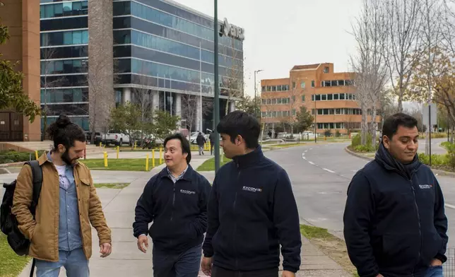 Actor Sebastián Solorza, who has Down syndrome and aims to run for president as an independent candidate, walks with coworkers in Santiago, Chile, Thursday, July 31, 2025. (AP Photo/Esteban Felix)