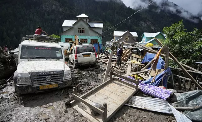 Household goods are strewn around next to buildings damaged by flash floods in Chositi village, Kishtwar district, Indian-controlled Kashmir, Friday, Aug. 15, 2025. (AP Photo/Channi Anand)