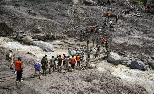Stranded pilgrims are helped across a water channel using a makeshift bridge a day after flash floods in Chositi village, Kishtwar district, Indian-controlled Kashmir, Friday, Aug. 15, 2025. (AP Photo/Channi Anand)