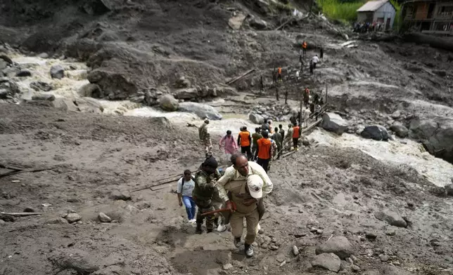 Stranded pilgrims cross a water channel using a makeshift bridge, the day after flash floods in Chositi village, Kishtwar district, Indian-controlled Kashmir, Friday, Aug. 15, 2025. (AP Photo/Channi Anand)