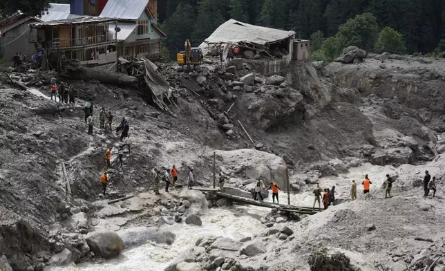 Stranded pilgrims are helped across a water channel using a makeshift bridge a day after flash floods in Chositi village, Kishtwar district, Indian-controlled Kashmir, Friday, Aug. 15, 2025. (AP Photo/Channi Anand)