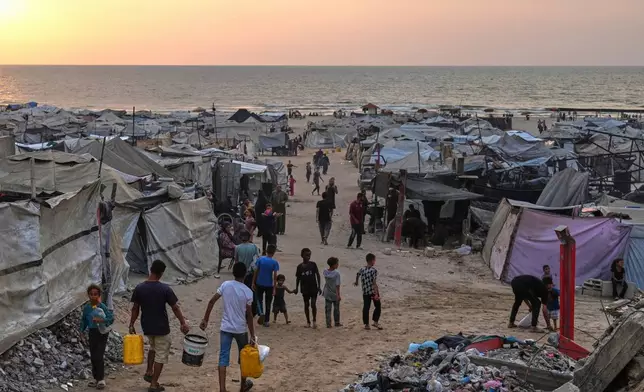 Displaced Palestinians walk through a makeshift camp along the beach in Gaza City, Sunday, Aug. 10, 2025. (AP Photo/Jehad Alshrafi)