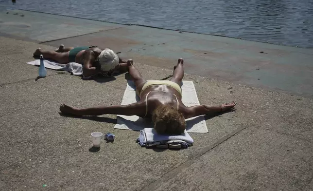 People sunbathe next to the Ada Ciganlija Lake in Belgrade, Serbia, Tuesday, Aug. 12, 2025. (AP Photo/Darko Vojinovic)