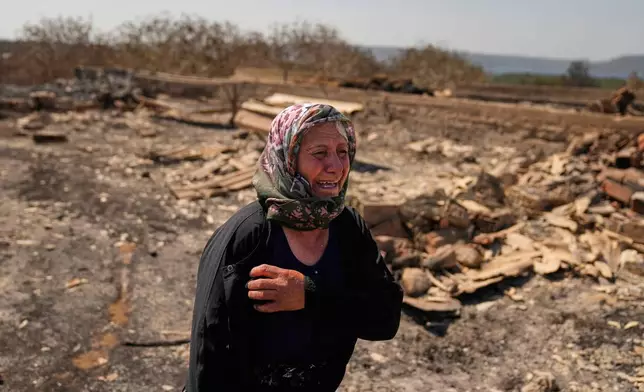 Local farmer Turkan Ozkan cries next to her destroyed home after a fire in Guzelyeli, in the outskirts of Canakkale, northwest Turkey, Tuesday, Aug. 12, 2025. (AP Photo/Khalil Hamra)