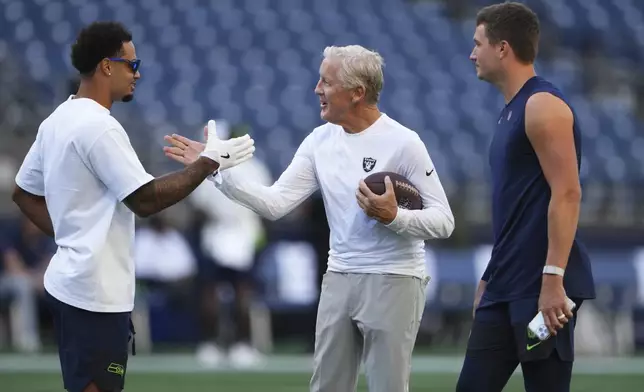 Seattle Seahawks wide receiver Jaxon Smith-Njigba, left, greets Las Vegas Raiders head coach Pete Carroll as Seattle Seahawks quarterback Drew Lock looks on before an NFL preseason football game Thursday, Aug. 7, 2025, in Seattle. (AP Photo/Lindsey Wasson)