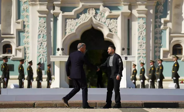 Canadian Prime Minister Mark Carney, front left, and Ukrainian President Volodymyr Zelenskyy, front right, shake hands as they take part in a ceremony on Independence Day in Sophia Square in Kyiv, Ukraine, on Sunday, Aug. 24, 2025. (Sean Kilpatrick/The Canadian Press via AP)