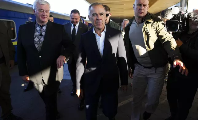 Canadian Prime Minister Mark Carney, center, walks with Ukrainian Minister for Foreign Affairs Andrii Sybiha, left, as he arrives in Kyiv, Ukraine, on Sunday, Aug. 24, 2025. (Sean Kilpatrick/The Canadian Press via AP)