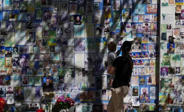 People visit the memorial wall of fallen defenders of Ukraine in Kyiv, Ukraine, on Saturday, Aug. 23, 2025. (Sean Kilpatrick/The Canadian Press via AP)