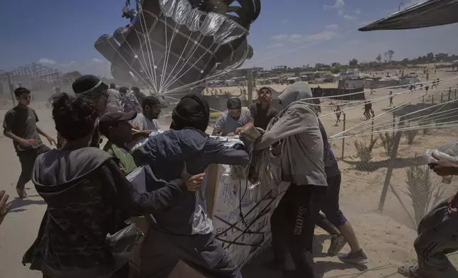 Palestinians rush to collect humanitarian aid airdropped into Deir al-Balah, central Gaza Strip, Aug. 5, 2025. (AP Photo/Abdel Kareem Hana)